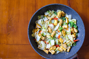Stir fry tofu and chinese cabbage in  the pan on a wood table, Indonesian dish eaten with rice.