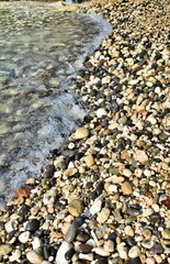 Pebbled shoreline dances with gentle waves.