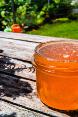 Honey Jar Filled with Bee Honey Standing on a Wooden Table in the Garden on a Hot Sunny Summer Day