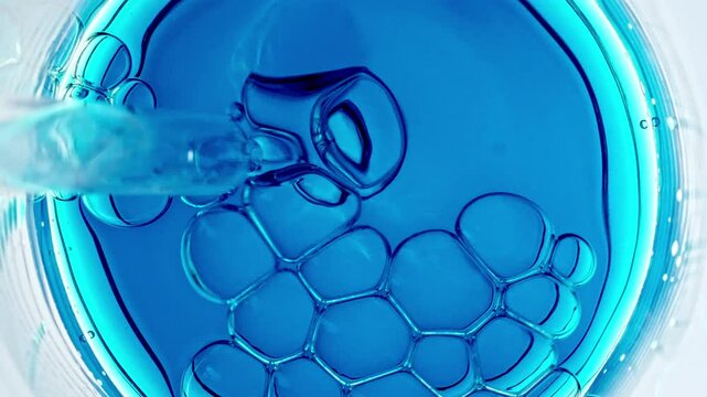 Transparent air Bubbles come out from lab pipet and bursting on the surface of clear fluid in Petri dish. The medicine concept, health care, treatment. Macro Shot of Natural Organic Cosmetics. 4k