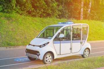 Electric police patrol car. A police electric golf cart sits empty with its special lights on on a bike path in a park or on the beach.