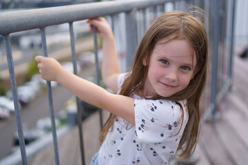 A small, beautiful schoolgirl missing one front tooth hung on the railing. Child health concept