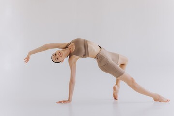 Sporty young woman with slim body doing yoga practice and stretching isolated on white background -...