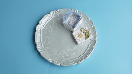 Plato de resina con una pequeña caja de regalo encima. Fondo azul