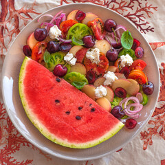 Fruit and vegetable plate with summer salad with peaches, soft diet goat cheese, multicolored and green tomatoes. onions, cherries, watermelon and basil. Sweet and salty taste, Mediterranean salads, h