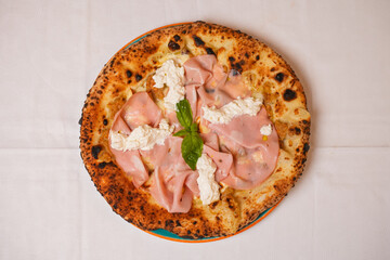 Pizza tradizionale napoletana con mortadella. ricotta, basilico fresco e mozzarella servita in una pizzeria © Vincenzo VAD