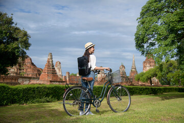 Young asian woman travel on holiday with bicycle, talking photo of world heritage site. Historical park of Ayutthaya, Thailand.