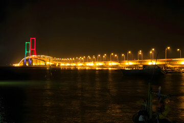 Experience the breathtaking beauty of the Suramadu Bridge as it illuminates the night sky. This architectural marvel, spanning the Madura Strait, serves as a vital link between Java and Madura islands