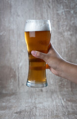 female hand raising beer on wooden background