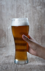 female hand raising beer on wooden background