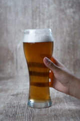female hand raising beer on wooden background