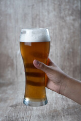 female hand raising beer on wooden background