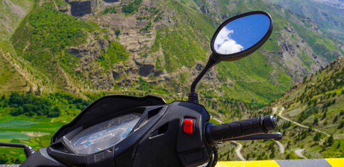 skyscape visible through vehicle's window with mountain landscape background