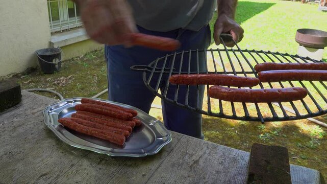 man puts raw merguez sausages on barbecue grill