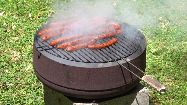 merguez sausages cooking on a barbecue grill with smoke