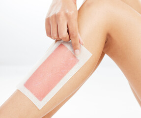 Woman, legs and wax beauty in studio, hair removal and healthy skincare on white background. Body wellness, hand and pull cosmetic product or grooming routine, smooth skin and strip or patch