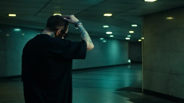 cool model guy looking around into camera, musicvideo concept, dark underground city location, male with shades