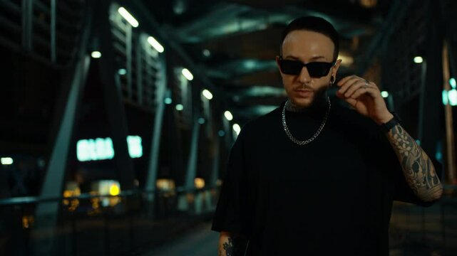 Rapper guy rubbing his hands, looking around, being cool, city night atmosphere.