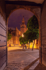 Naklejka premium Night view of Giralda Tower framed by an archway in Seville, Spain