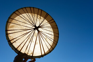 An image of a handmade leather meditation drum being held up against a bright blue sky. 