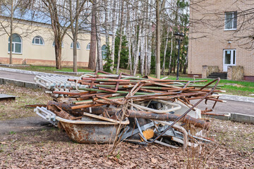 Heap with rusty pipes, old bathtubs, cast iron radiators, in yard among buildings
