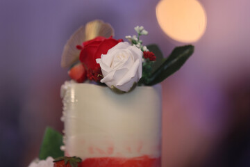 white fluffy wedding  step cheese cake decorated with red and white rose icing