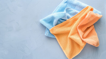 Soft and vibrant orange and blue microfiber cloths rest gently on a textured, light-gray surface.