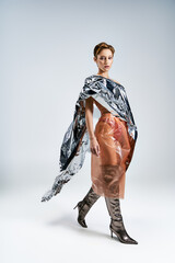A woman confidently walks in a silver cape and peach dress