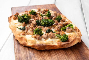 Pinsa romana bianca condita con salsiccia di maiale e broccoli, cibo italiano, gastronomia europea 