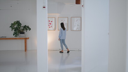 Fototapeta premium Gallery visitor looking paintings on weekend. Woman walking contemporary museum