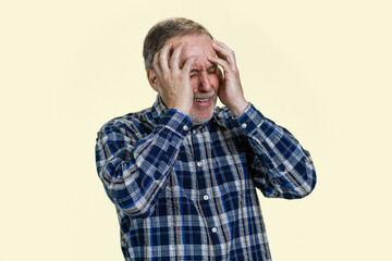 Portrait of senior man holds his head with both hands because of headache or disappontment. Isolated on white.