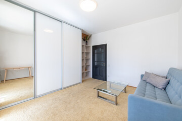 Minimalism Children, Young Adult Living Room Interior. Couch and Table. Coffee Table, Wardrobe, Left on the Right Side. Carpet. Black Wooden Door.