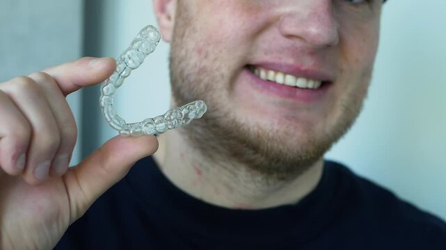 Straightening teeth for a beautiful smile. Teeth aligner for people. A man with a mouthguard in his teeth. Transparent protector.