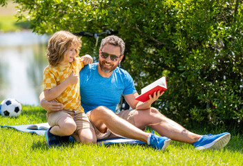 Father and son explore book in nature beauty. quality time for father and son. Father and son connect through stories in nature. Father and son bonding over outdoor literature. Studying under the sun