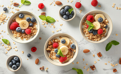 Healthy breakfast bowls with yogurt, granola, banana slices, blueberries, and raspberries on a light background.