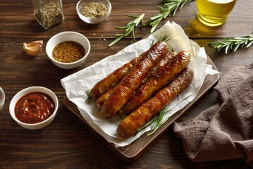 Roasted juicy sausages on wooden table