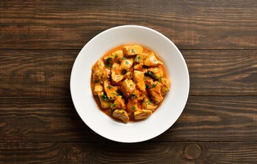  Indian dish chicken tikka masala on plate on wooden background