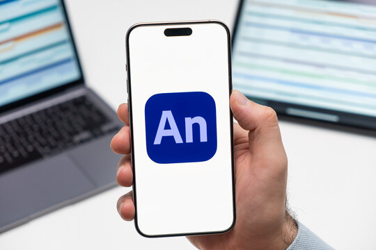 PRAGUE, CZECH REPUBLIC - JANUARY 21 2024: Adobe Animate CC logo on the screen of smartphone in mans hand on the workplace background. 