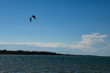 Kitesurfer is riding a wave on a sunny day with blue sky