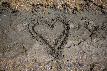 Heart drawn in the sand on a beach being washed away by the ocean waves, representing lost love