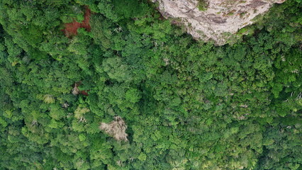 Obraz premium Aerial green forested hillsides with steep cliffs. Rugged mountains terrain.