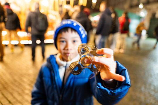 Asian boy playing with fidget spinner at Christmas market