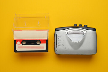 A silver cassette tape recorder sits next to a clear plastic case