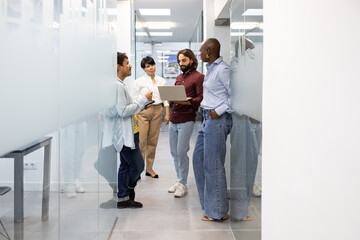 Diverse team discussing project in modern hallway