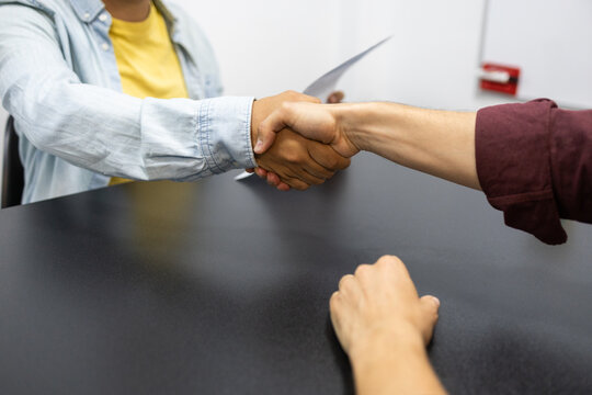 Two people shaking hands at a table in an office setting