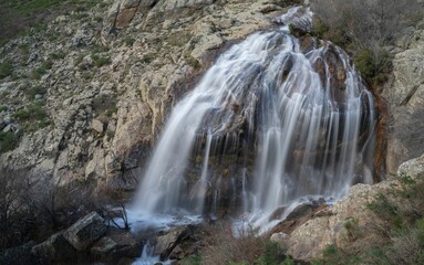 Obraz premium A stunning waterfall cascading down rocky cliffs in a mountainous landscape