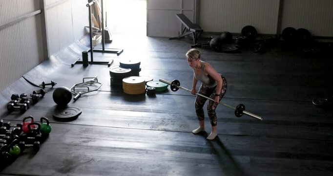Mature Woman Doing Exercise with Barbell At The Gym