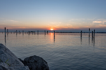 Serene Sunset on the Sea in Grado: Splendid Reflections and Colors Admired from a Rocky Pier.