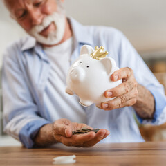 Senior man count money from the piggy bank and save money at home