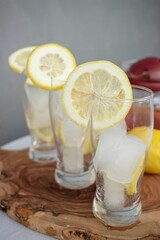 Close-up of three glasses with ice and lemon slices on a wooden board